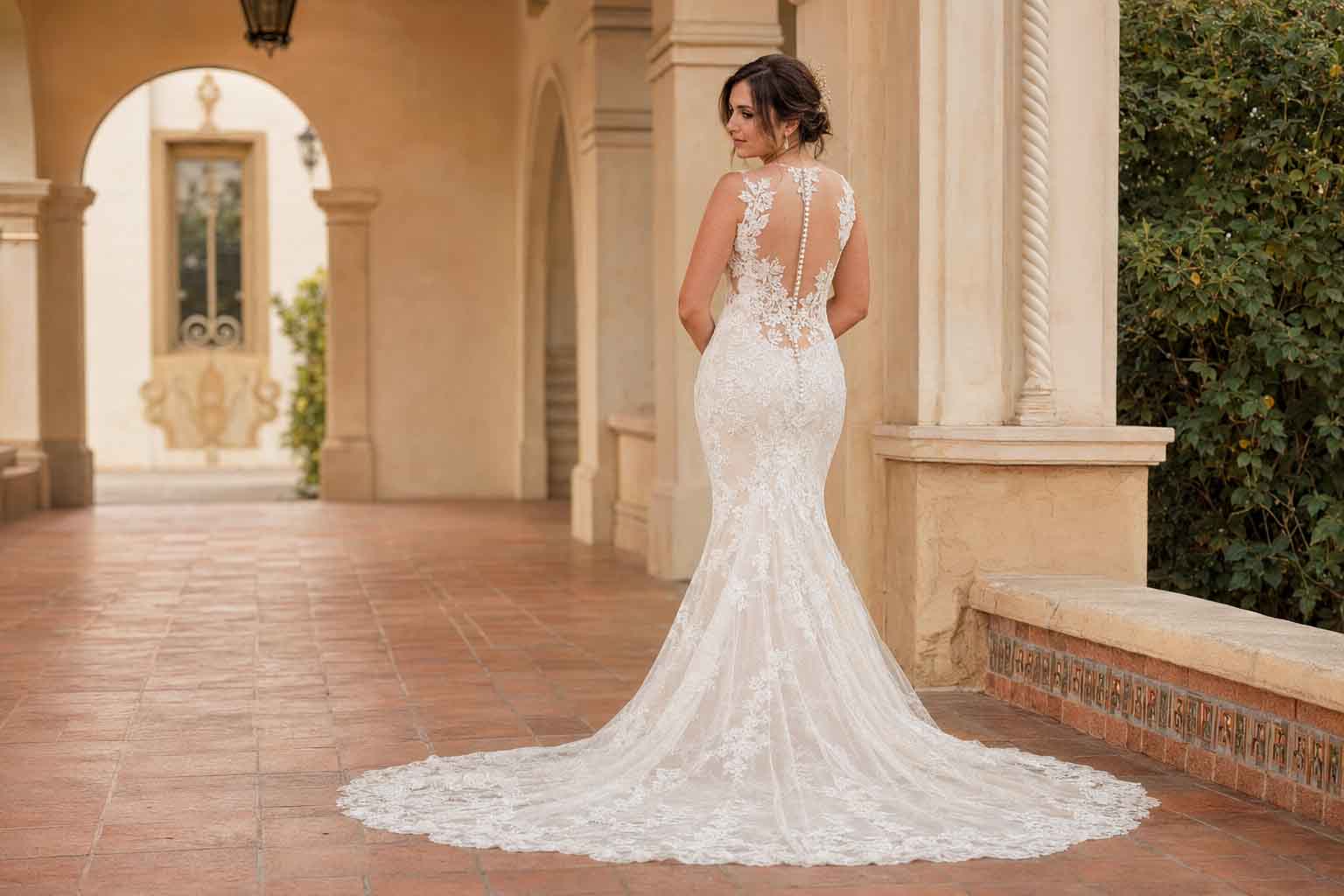 Bride in a lace fit-and-flare wedding dress beneath Spanish-style arches at Balboa Park