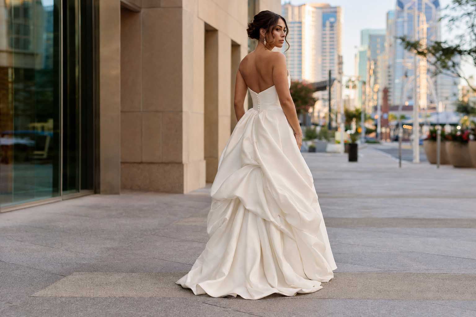 Bride wearing a French under-bustle wedding dress against a downtown San Diego background.