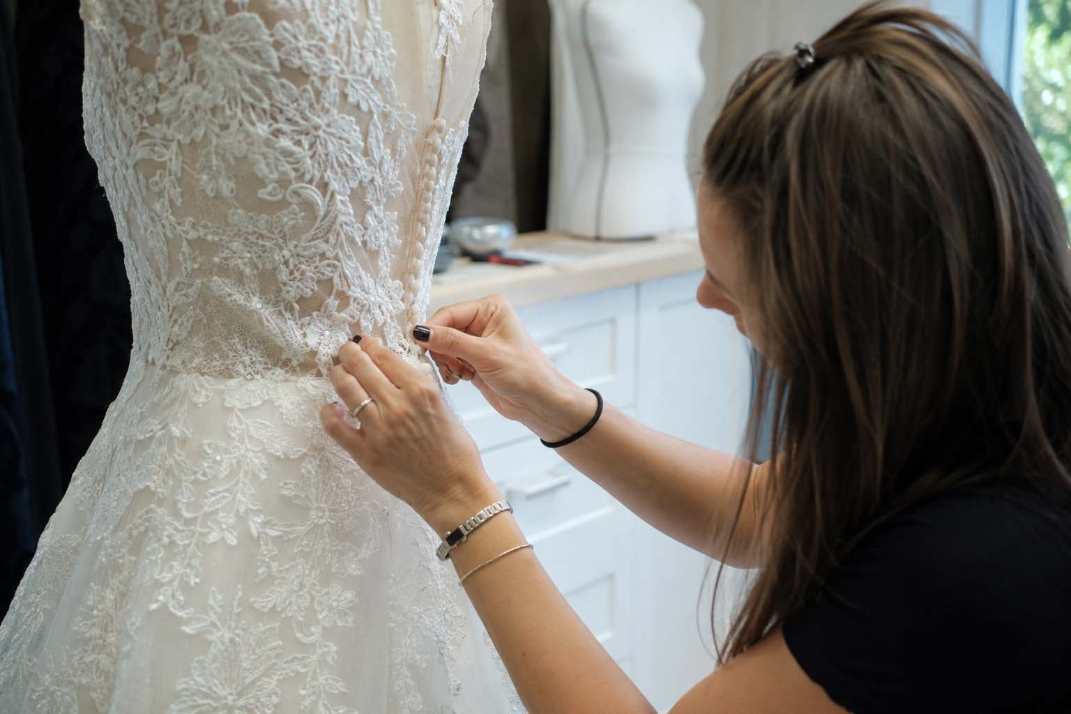 Bridal specialist working around lace appliqué on a wedding gown seam