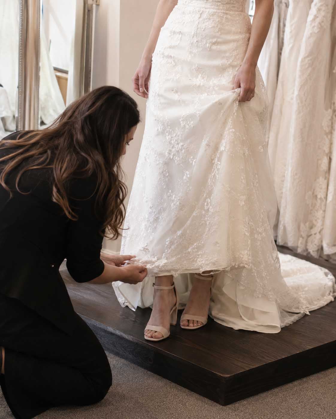 Wedding gown hem being evaluated while the bride wears wedding shoes