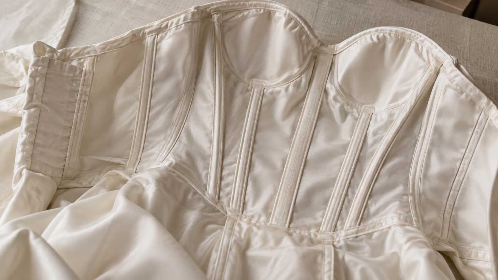 Close-up of ivory satin, textured crepe, sheer organza, and fine tulle draped across a bridal worktable.